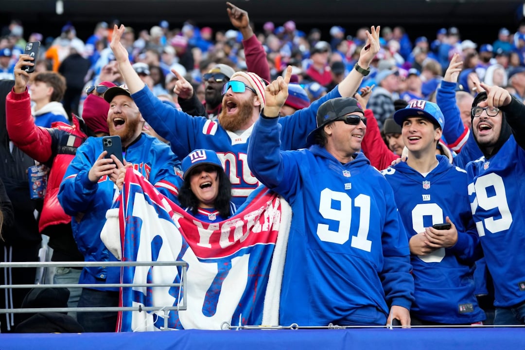Torcedores dos NY Giants uniformizados vibram na arquibancada
