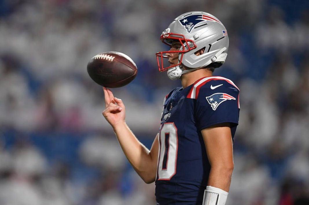 Jogador dos Patriots em perfil equilibra a bola nos dedos indicador e anelar