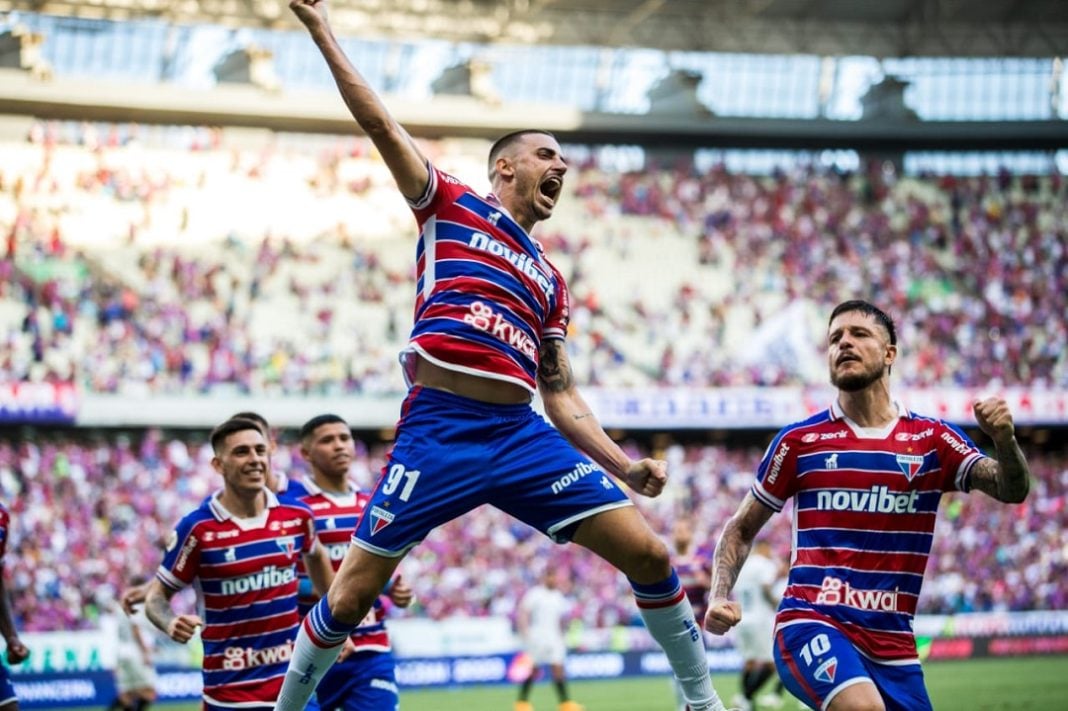 Jogadores comemoram gol do Fortaleza, ao centro, atleta salta vibrante com punho para o alto